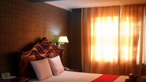 A hotel room with a large bed, a nightstand, a lamp, and a window with curtains. - Seoul hotel Mongolia (Ulaanbaatar)