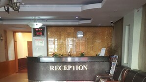 A reception area with a reception desk, a clock, and a red carpet leading to a seating area. - Seoul hotel Mongolia (Ulaanbaatar)