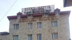 A hotel with a stone facade, multiple windows, and a sign indicating a karaoke room. - Seoul hotel Mongolia (Ulaanbaatar)
