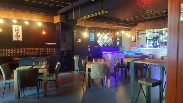 A restaurant interior with booths and tables, a bar area with blue lighting, and a brick wall with framed pictures. - Seoul hotel Mongolia (Ulaanbaatar)