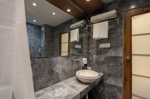 Un baño moderno con lavamanos de mármol, toallero y espejo.