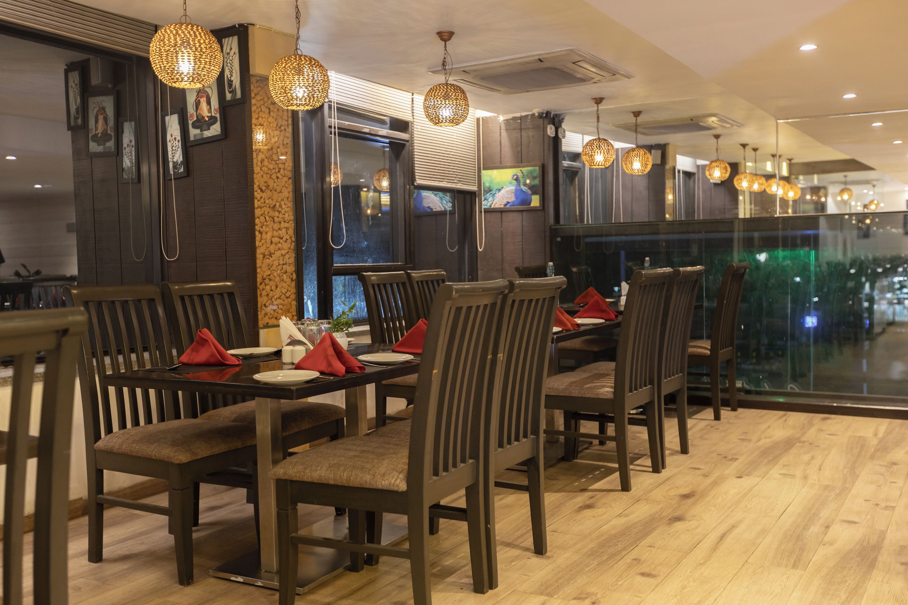 A restaurant with wooden furniture, red napkins, and hanging lights.