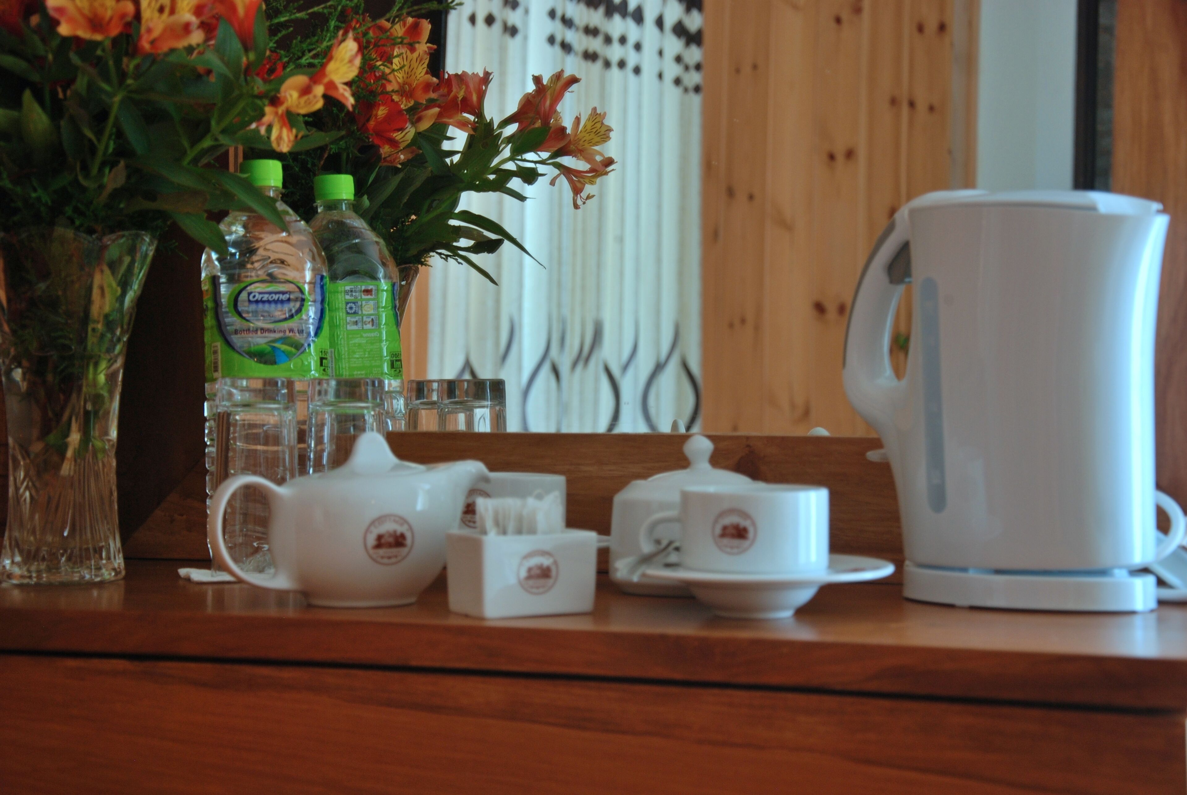 Ein Tisch mit einem Teeservice, zwei Wasserflaschen und einer Vase mit Blumen.