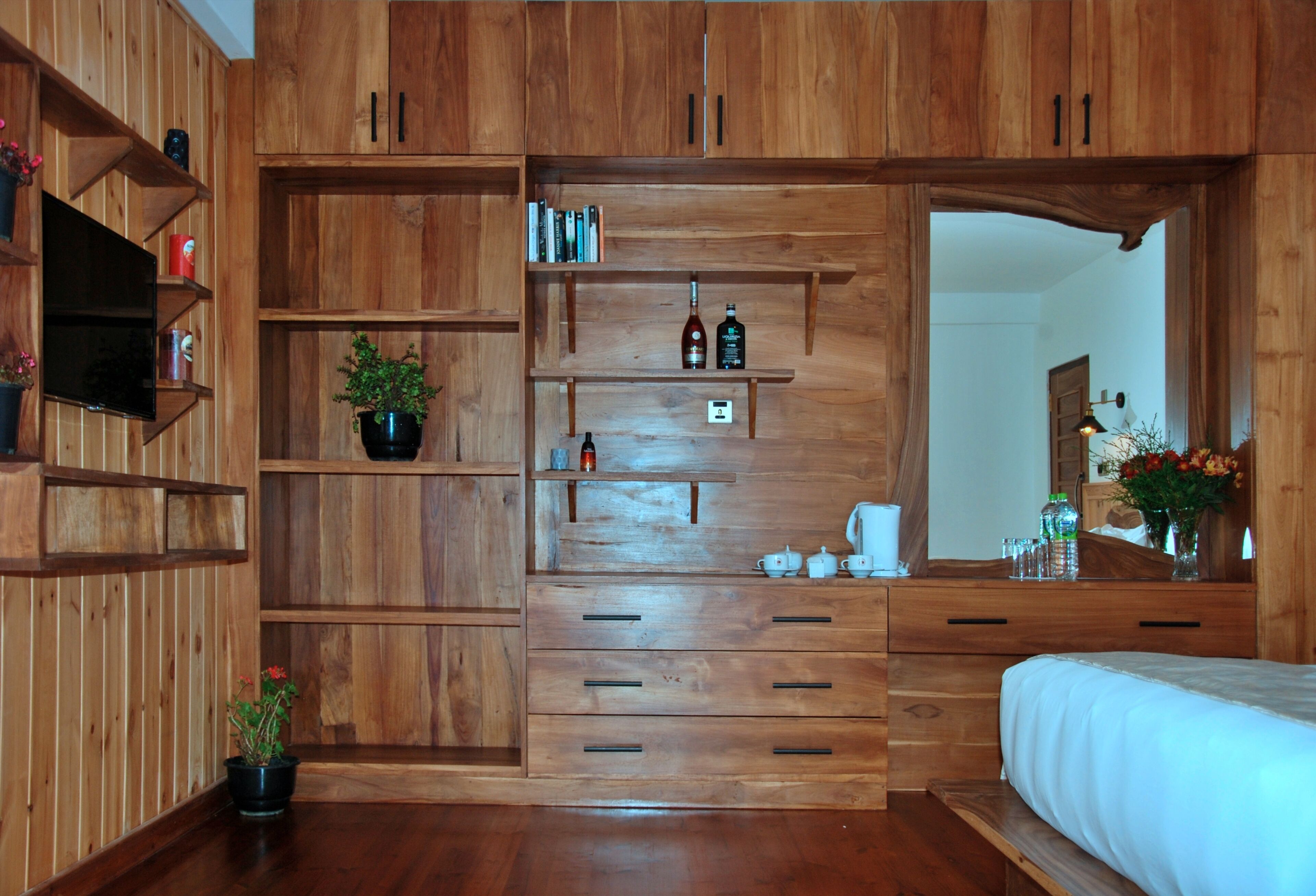 A bedroom with wooden furniture, a television, and a large mirror.