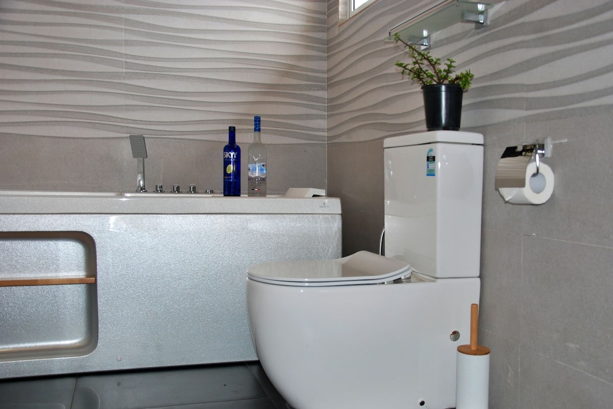 A modern bathroom with a white toilet, a sink with a mirror, and a toilet paper holder.
