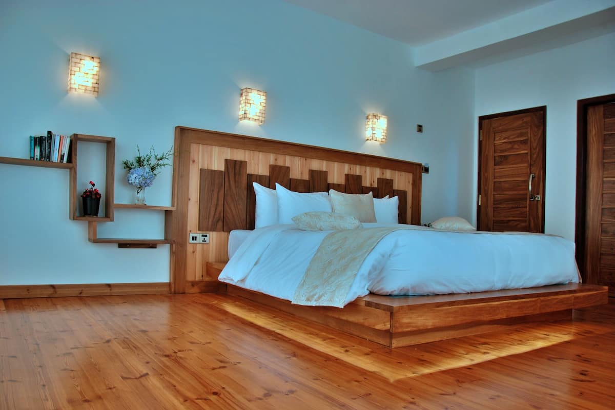 A bedroom with a wooden headboard, a bed with white linens, and two wall-mounted light fixtures.
