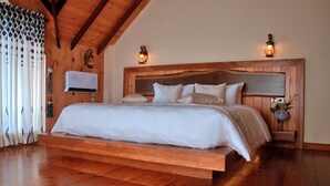 A bedroom with a wooden bed frame, a mounted air conditioner, and two wall-mounted lamps. - Cottage San Francesco (Nuwara Eliya)