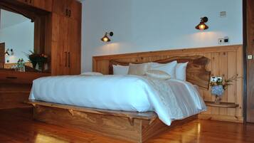 A wooden bed with a headboard, two bedside lamps, and a nightstand with a vase of flowers.