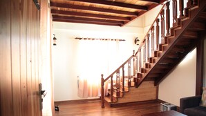A wooden staircase with a handrail, a wooden floor, and a ceiling with exposed beams. - Cottage San Francesco (Nuwara Eliya)