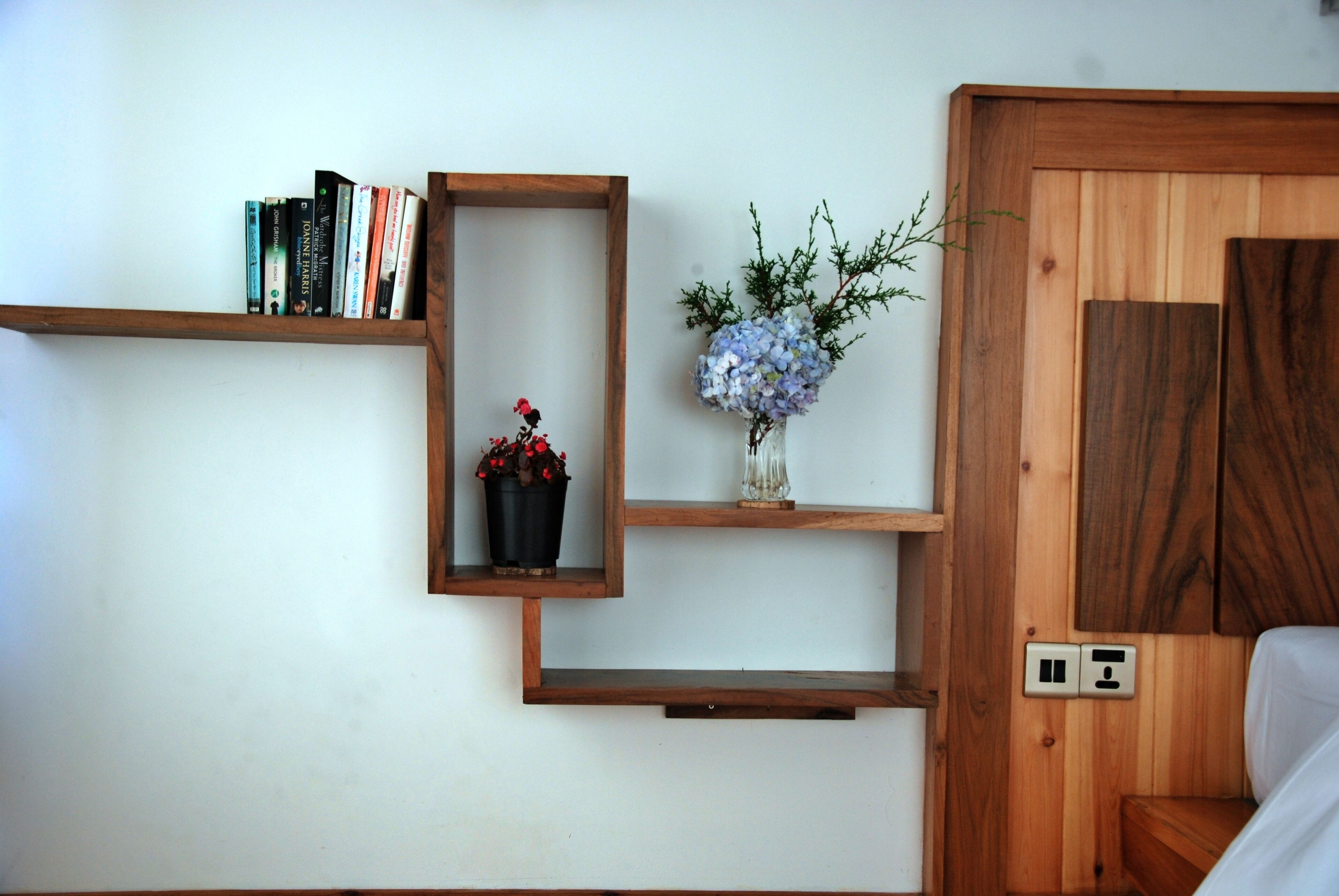 Une pièce avec des étagères en bois remplies de livres et un vase avec des fleurs.