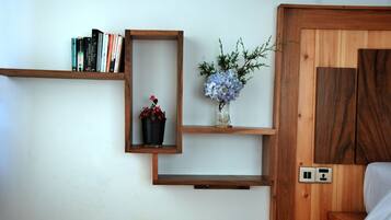 Une pièce avec des étagères en bois remplies de livres et un vase avec des fleurs.