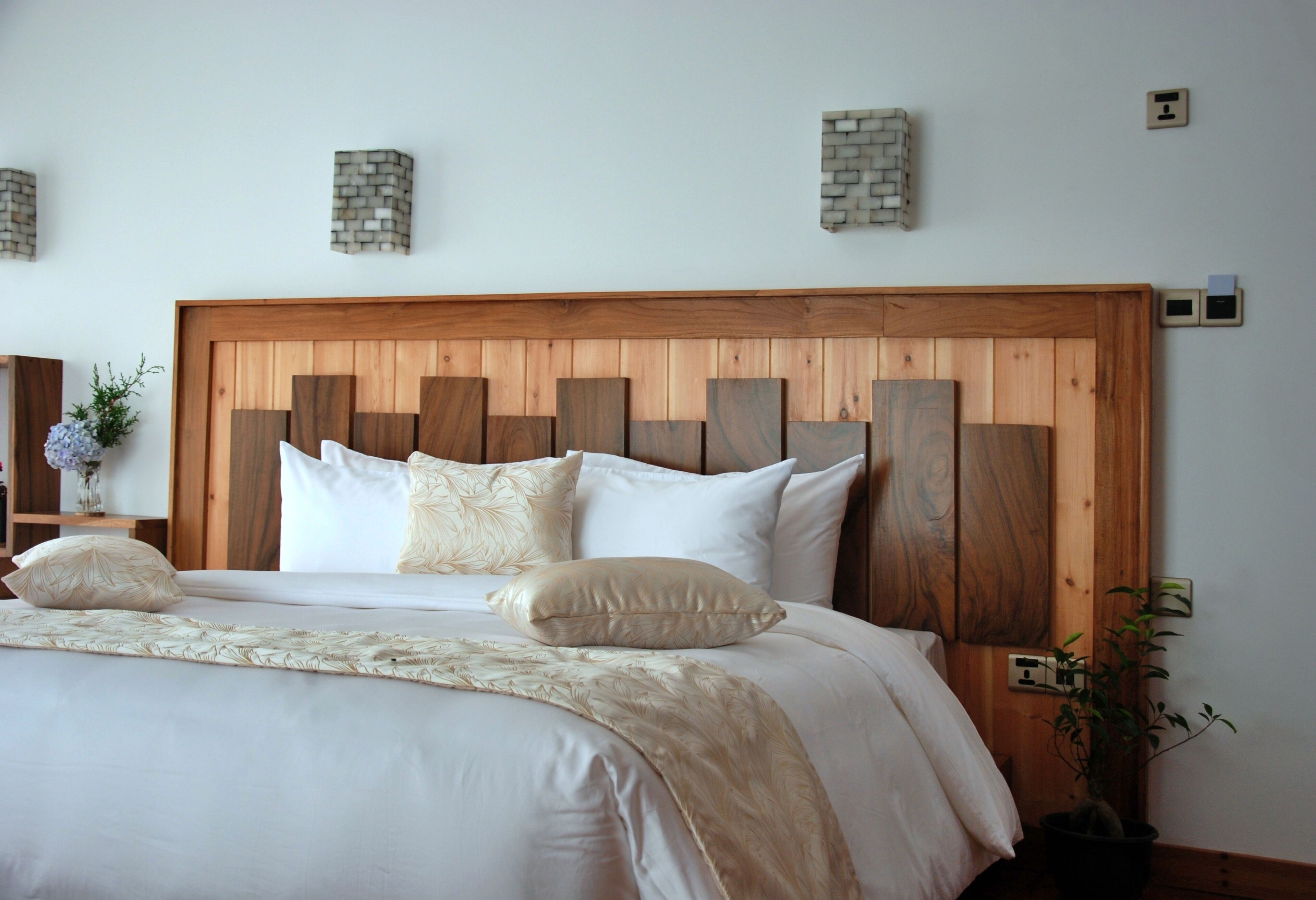 A neatly made bed with a wooden headboard, white bedding, and decorative pillows.