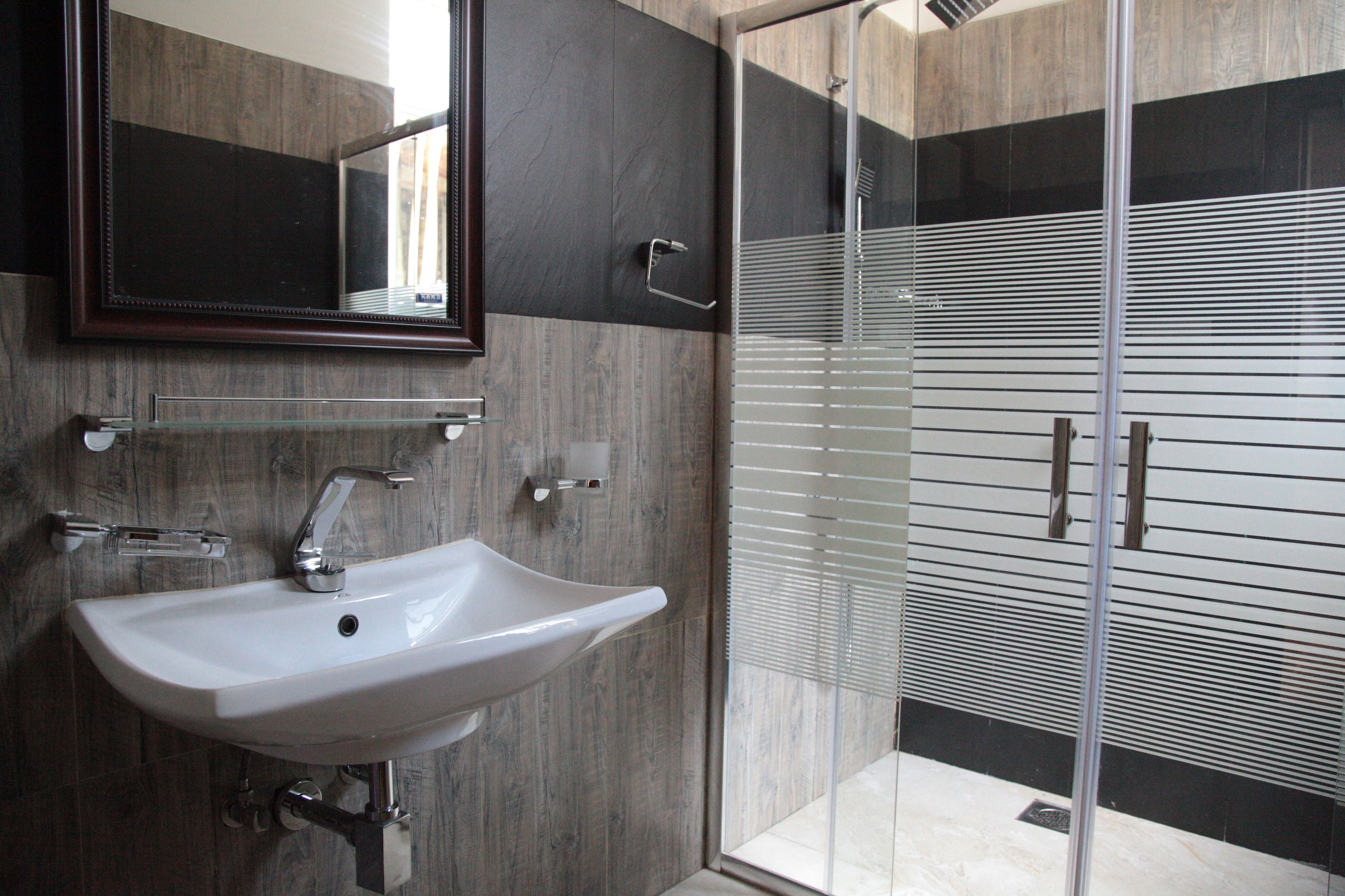 A modern bathroom with a white sink, a large mirror, and a glass-enclosed shower area.