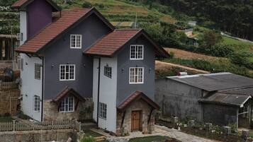 A two-story house with a stone foundation, a red-tiled roof, and a small front porch.