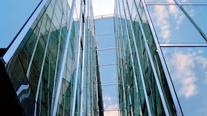 A modern glass building with a symmetrical facade and reflective surfaces. - Astoria Lucerne (Lucerne)