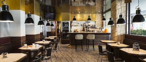 Un restaurante con cabinas y mesas, una zona de bar y un suelo con diseño.