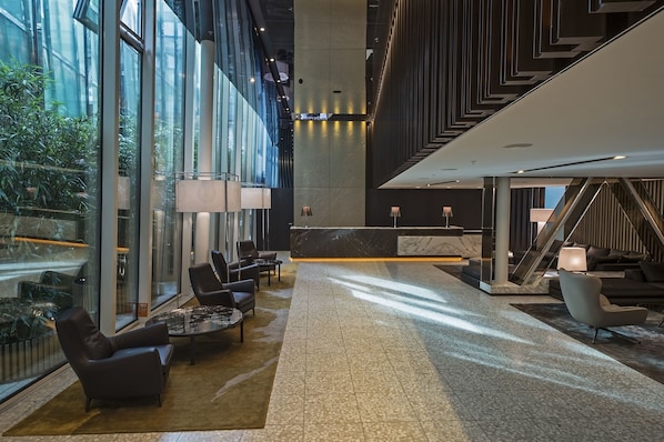 A spacious lobby with a reception desk, seating area, and a staircase.