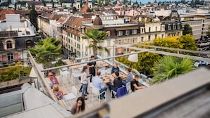 A rooftop terrace with outdoor seating, overlooking a cityscape with historic buildings. - Astoria Lucerne (Lucerne)