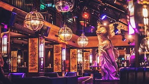 A bar area with multiple hanging spherical chandeliers, a statue, and traditional decor. - Astoria Lucerne (Lucerne)