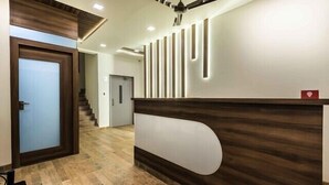 Ein Empfangsbereich mit einem Holzbüro, einem Deckenventilator und einer Treppe im Hintergrund.