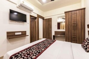 Une chambre d’hôtel comprenant un lit, un téléviseur fixé au mur, une armoire et un miroir.