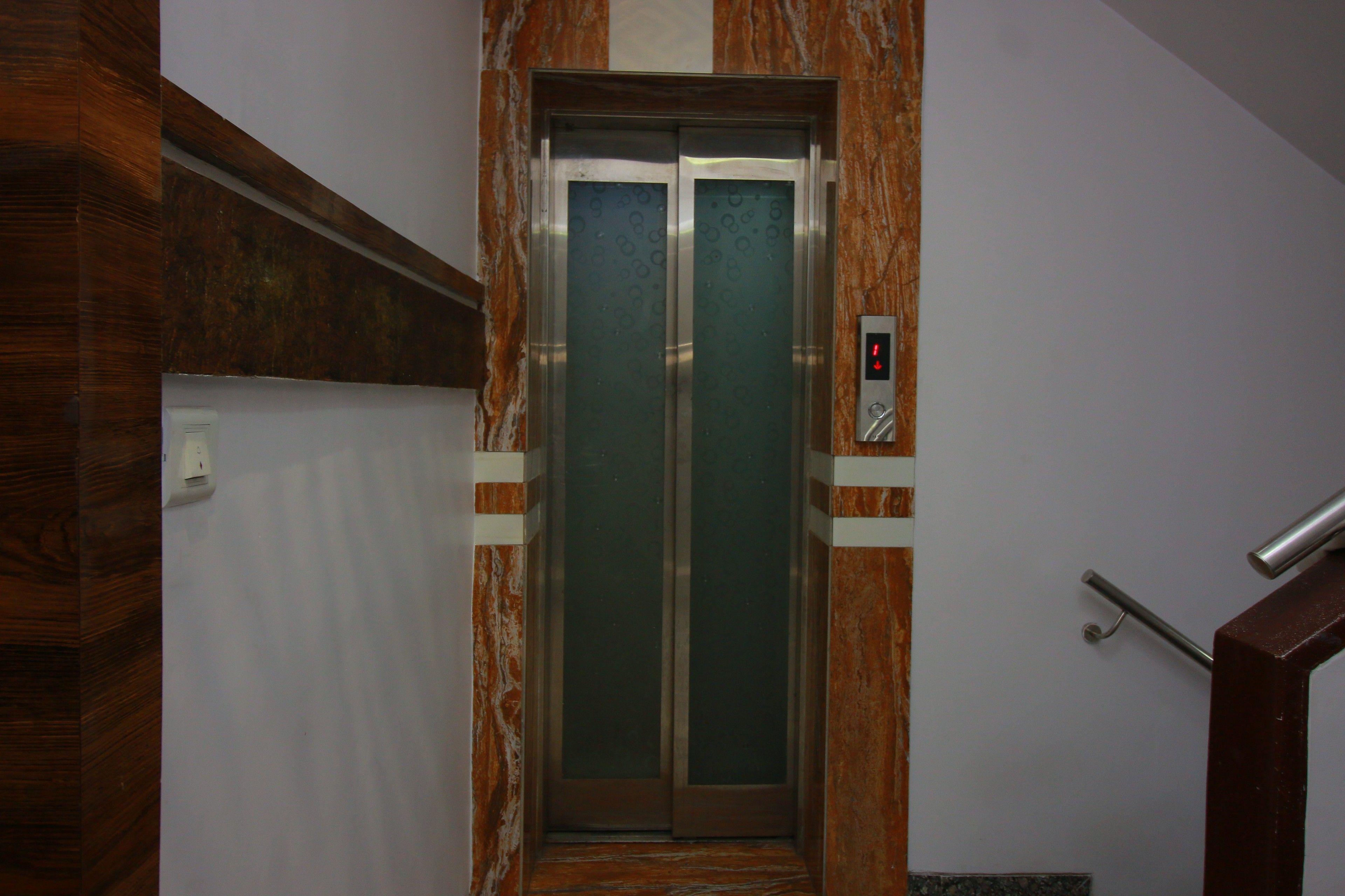 An elevator with a marble wall and a digital control panel.