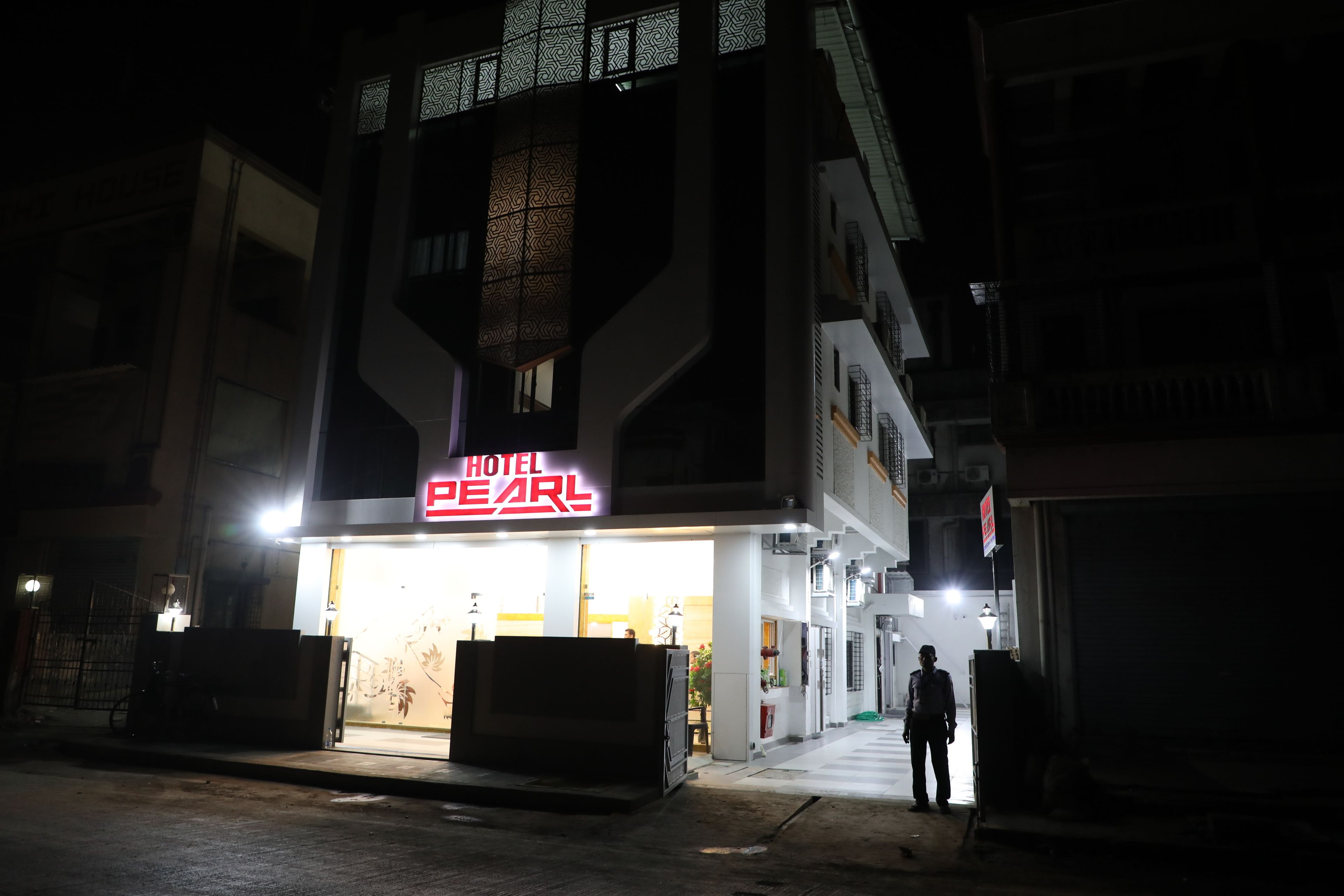 A hotel named "HOTEL PEARL" with a modern facade and a brightly lit entrance.
