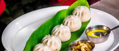 A plate of dumplings with two small bowls of sauce and nuts.