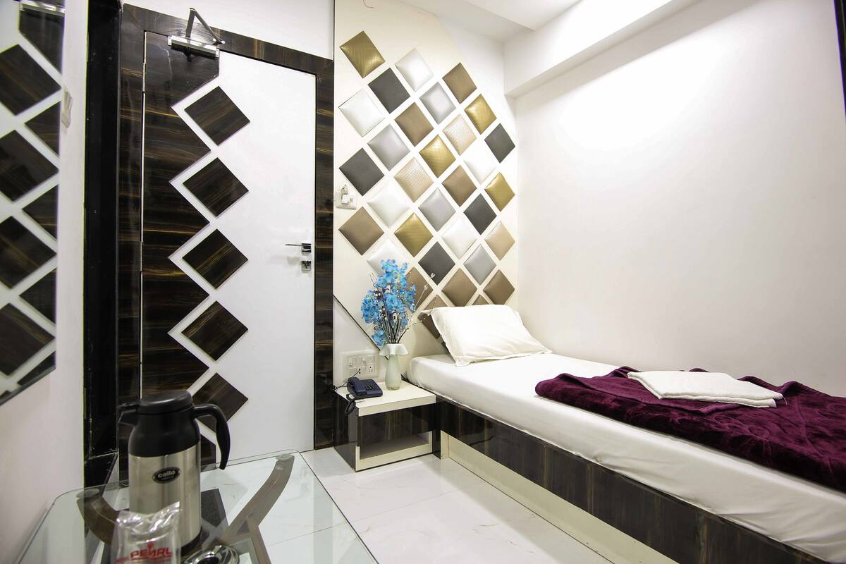A modern bedroom with a bed, bedside table, and a decorative wall panel.
