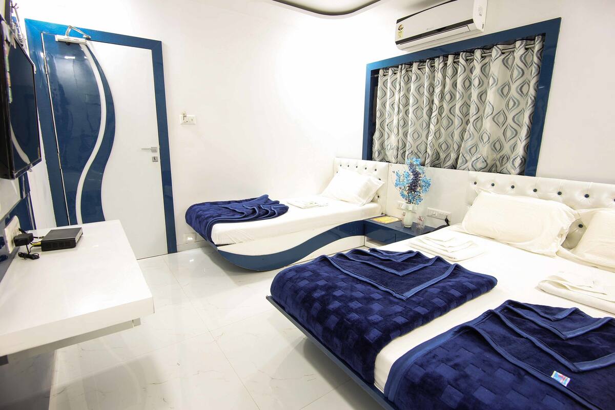 A hotel room with two beds, a desk, and a shower.