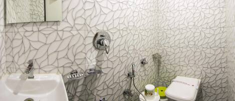 A bathroom with a white marble wall, a sink, a toilet, and a shower.