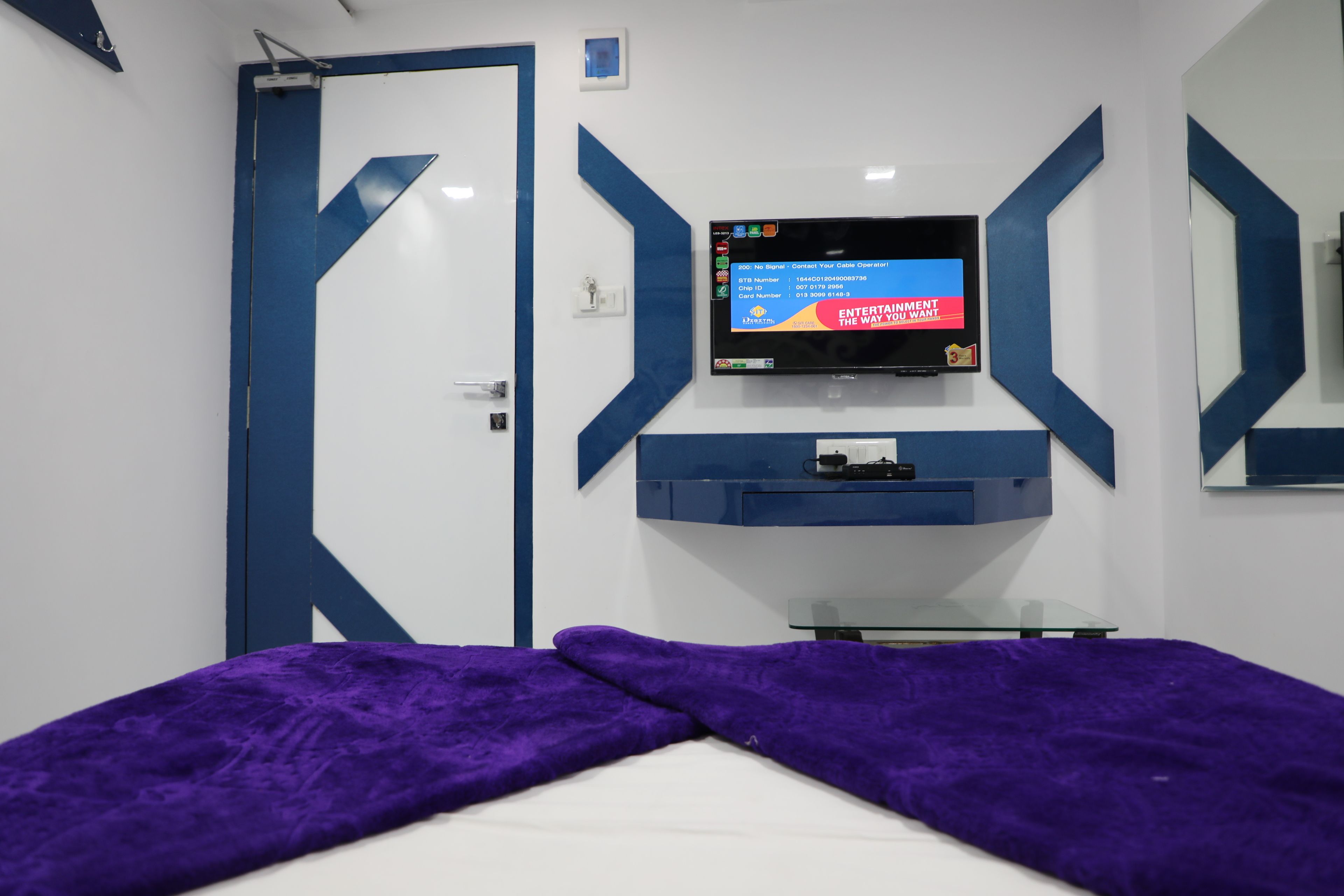 Une chambre avec un lit, un téléviseur fixé au mur et une petite table.