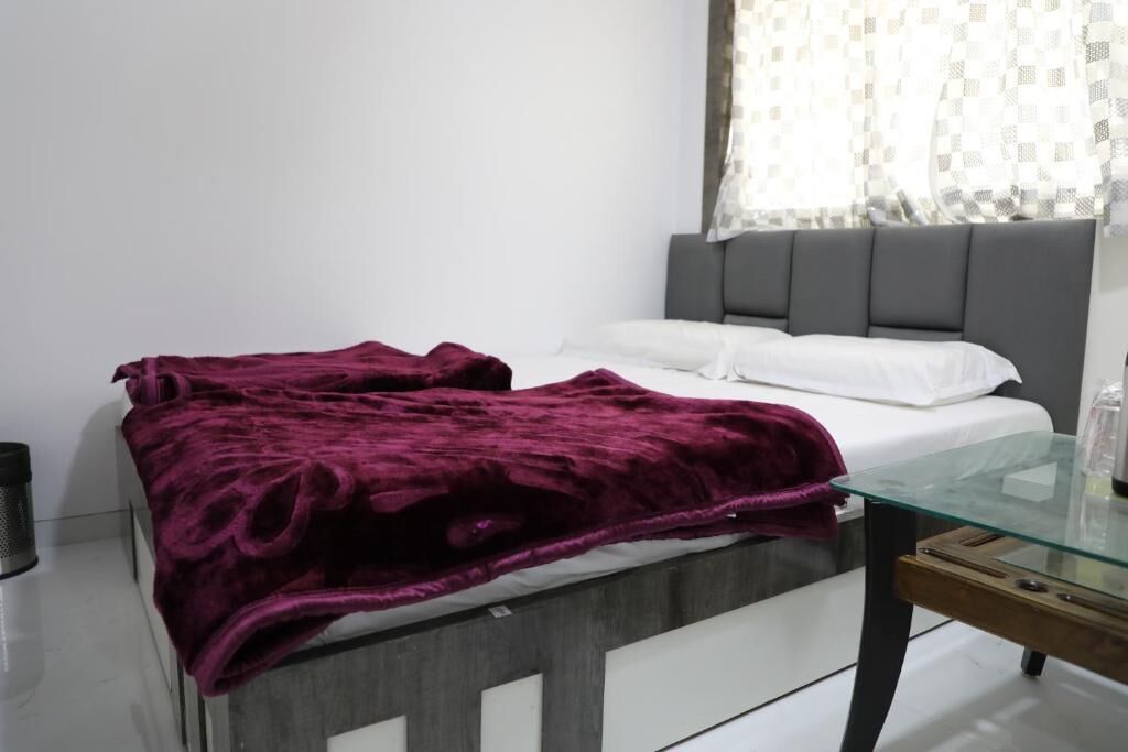 A bedroom with a bed, a glass table, and a grey headboard.