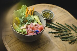 A bowl of assorted raw seafood and vegetables on a wooden table. - MAJO Private Villas (Gili Trawangan)