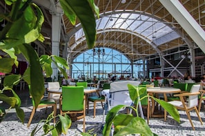 An indoor dining area with high ceilings, large windows, and green chairs. - Phoenicia Royal (Navodari)