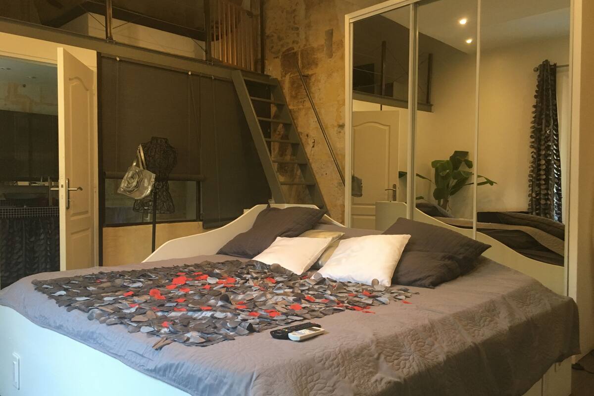 A bedroom with a bed, a ladder, a wardrobe, and a large mirror.