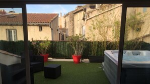 A view of a courtyard with artificial grass, potted plants, a hot tub, and outdoor furniture. - Les Chambres de Naevag (St.-Rémy-de-Provence)