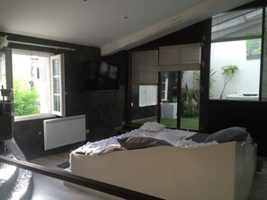 A bedroom with a bed, a radiator, a TV, and large windows. - Les Chambres de Naevag (St.-Rémy-de-Provence)