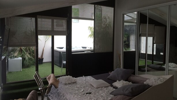 A modern bedroom with a large bed, sliding glass doors leading to a balcony, and a view of the outdoors. - Les Chambres de Naevag (St.-Rémy-de-Provence)
