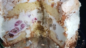 Una porción de pastel con relleno cremoso y base desmenuzable, sobre un plato de metal.