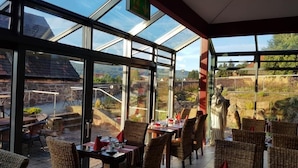 Un restaurante con terraza, amplias ventanas y vistas del paisaje circundante.