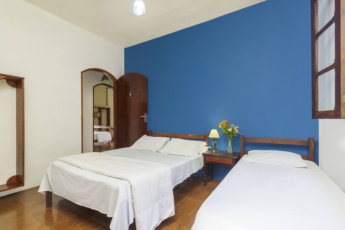 Une chambre d’hôtel avec deux lits, une armoire en bois, une table de chevet avec une lampe et un miroir.