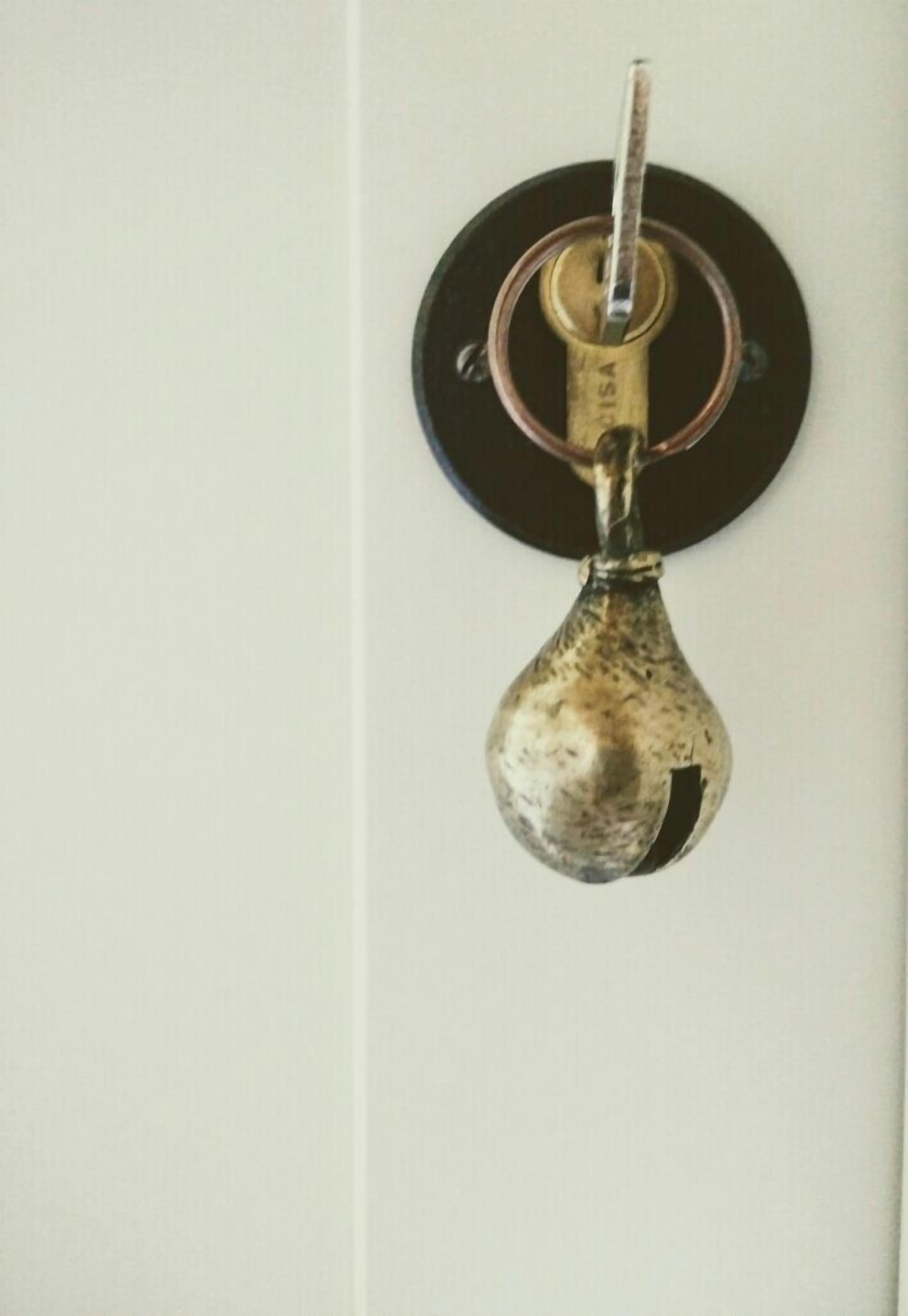 A key hook with a key inserted, mounted on a wall.
