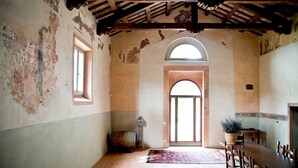 An interior with a rustic wooden ceiling, a large arched doorway, and a dining area with wooden furniture. - Azienda Agricola Baccagnano (Brisighella)