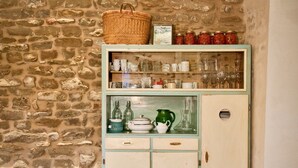 A stone wall with a vintage cabinet containing glassware and kitchen items. - Azienda Agricola Baccagnano (Brisighella)