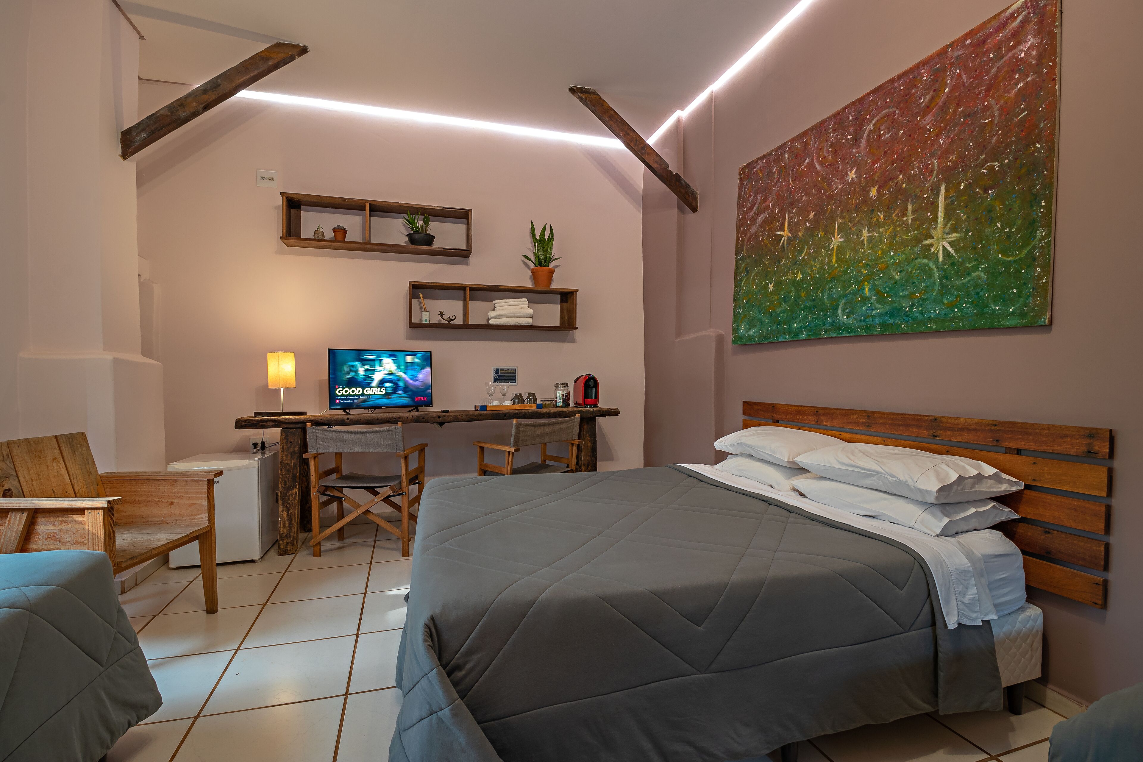 A bedroom with a bed, a desk with a computer, a chair, and a TV.