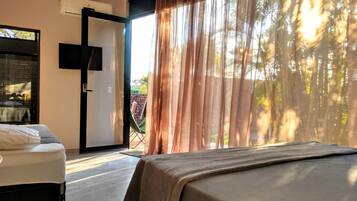 Habitació d'hotel amb un llit, una televisió i una porta que dona a una zona exterior amb una cadira.