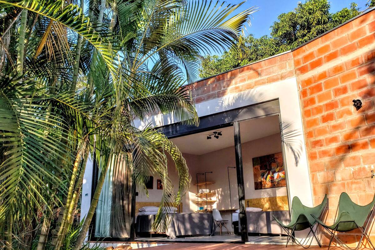 Un patio moderno al aire libre con muro de ladrillo, terraza de madera y zona de estar con sillas.