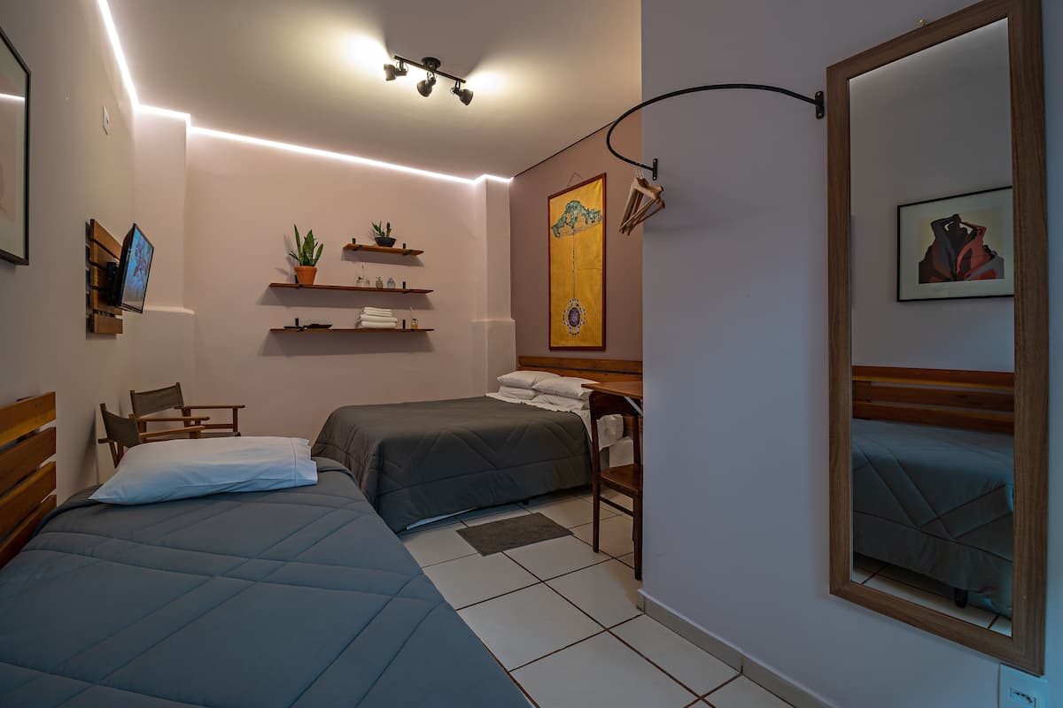 Un dormitorio con dos camas, un escritorio, estanterías con plantas y obras de arte en las paredes.