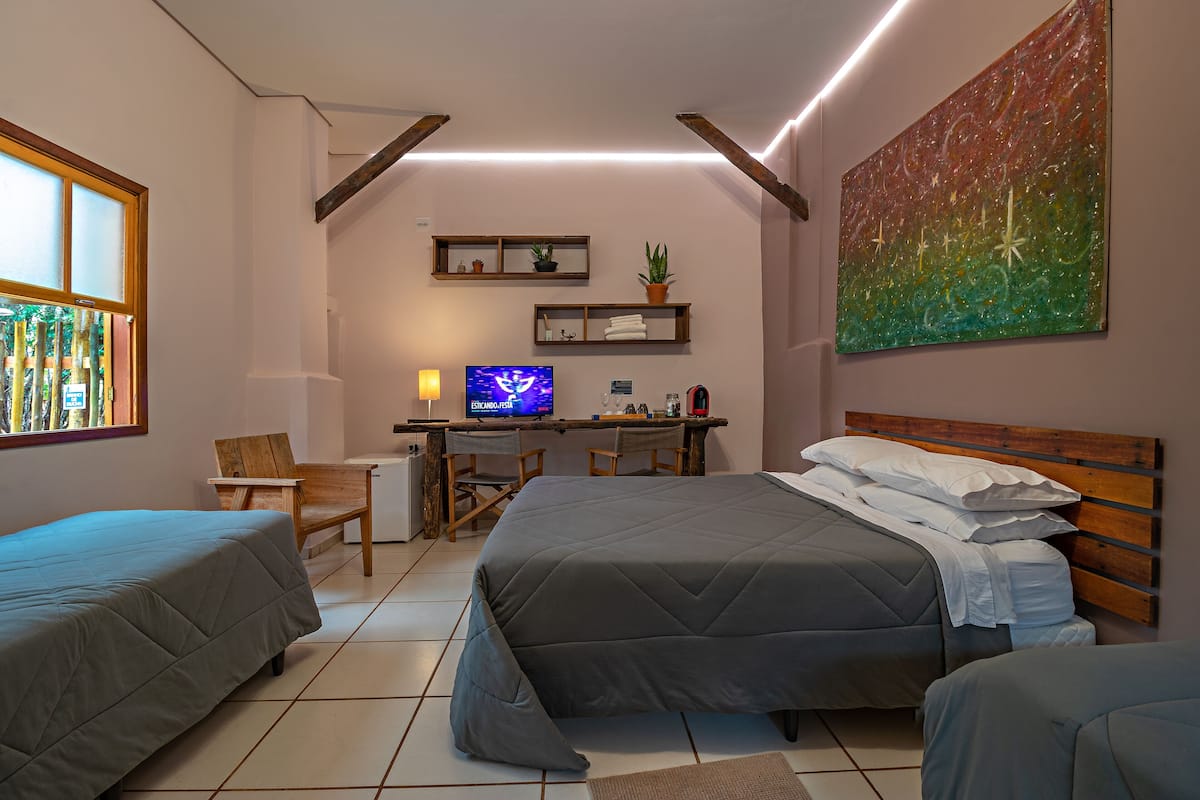 Un dormitorio con dos camas, un escritorio, un televisor y un cuadro.